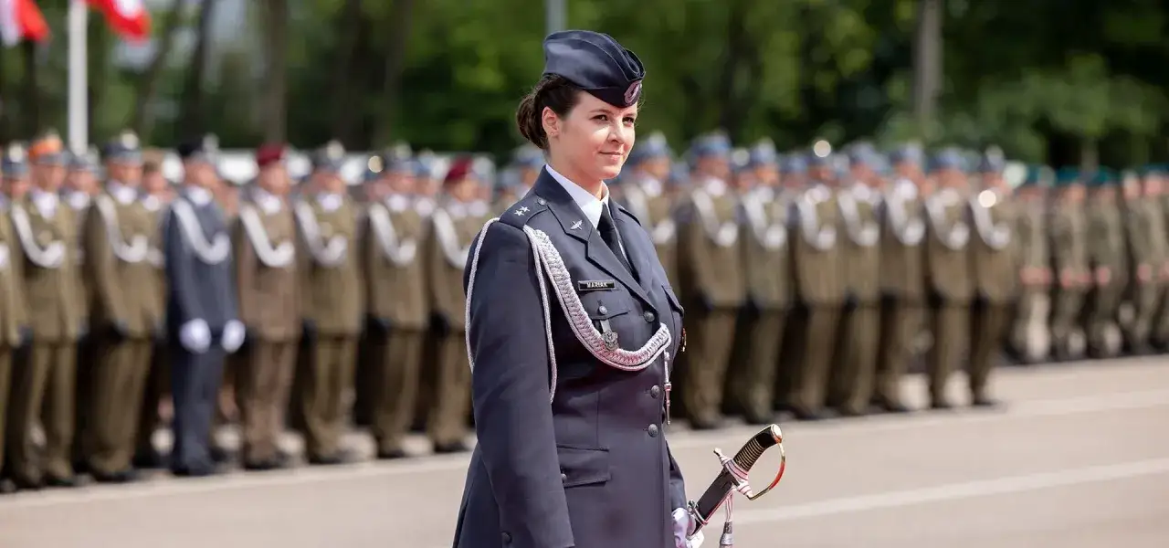 Oficerka w mundurze z szablą, na tle szeregu żołnierzy. Czy po studiach wojskowych trzeba iść do wojska?
