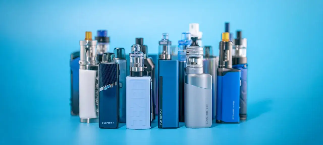 Colección de vapers y dispositivos para generar humo vaper, en tonos azules y plateados, sobre fondo azul.