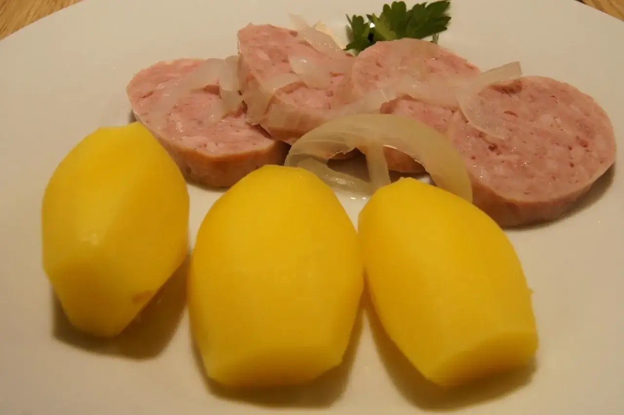 Tranches de saucisson à cuire au four vin blanc, accompagnées de pommes de terre vapeur et d'oignons.