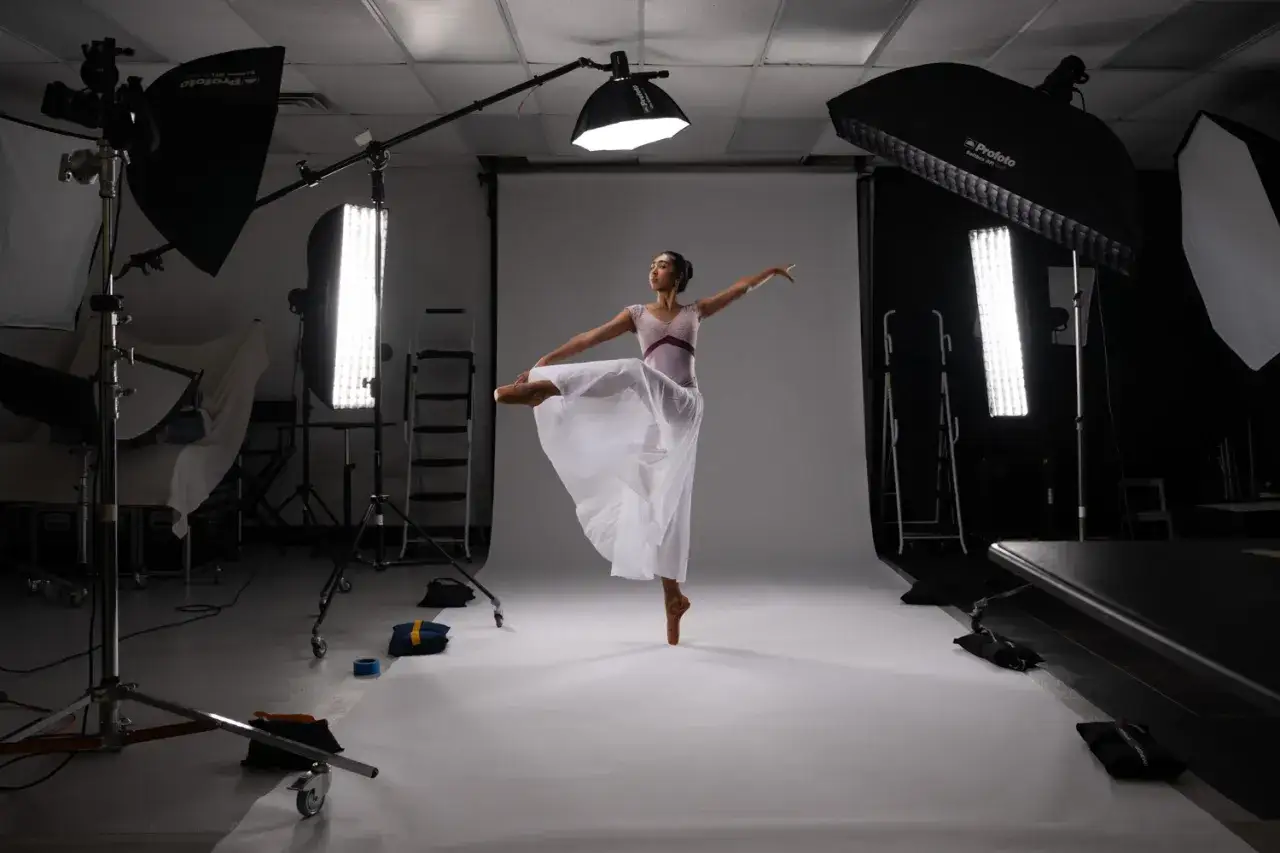 Una ballerina in posa in uno studio fotografico, circondata da luci e attrezzature. Questo è un esempio di come creare un video dance.