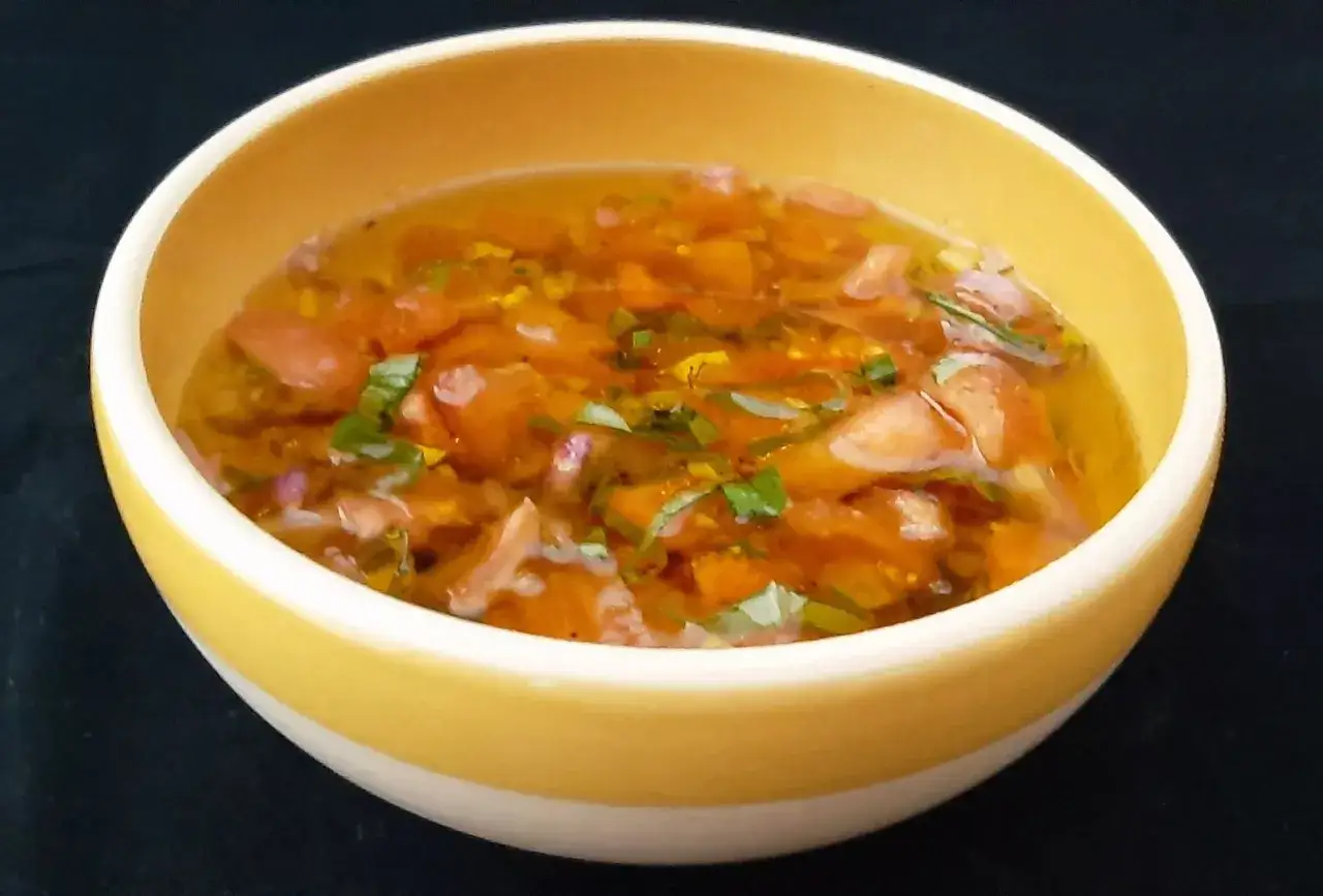 Un bol jaune contient une sauce vierge aux tomates coupées, oignons et herbes. Une recette simple et fraîche.