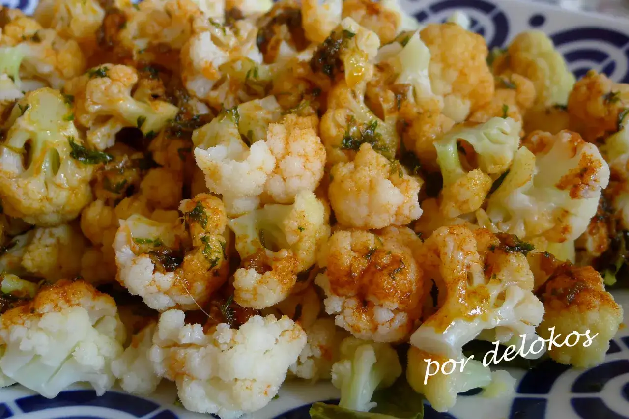 Coliflor al ajillo, con trozos tiernos y dorados, salpicados de perejil fresco y un toque de pimentón. Un plato sencillo y delicioso.