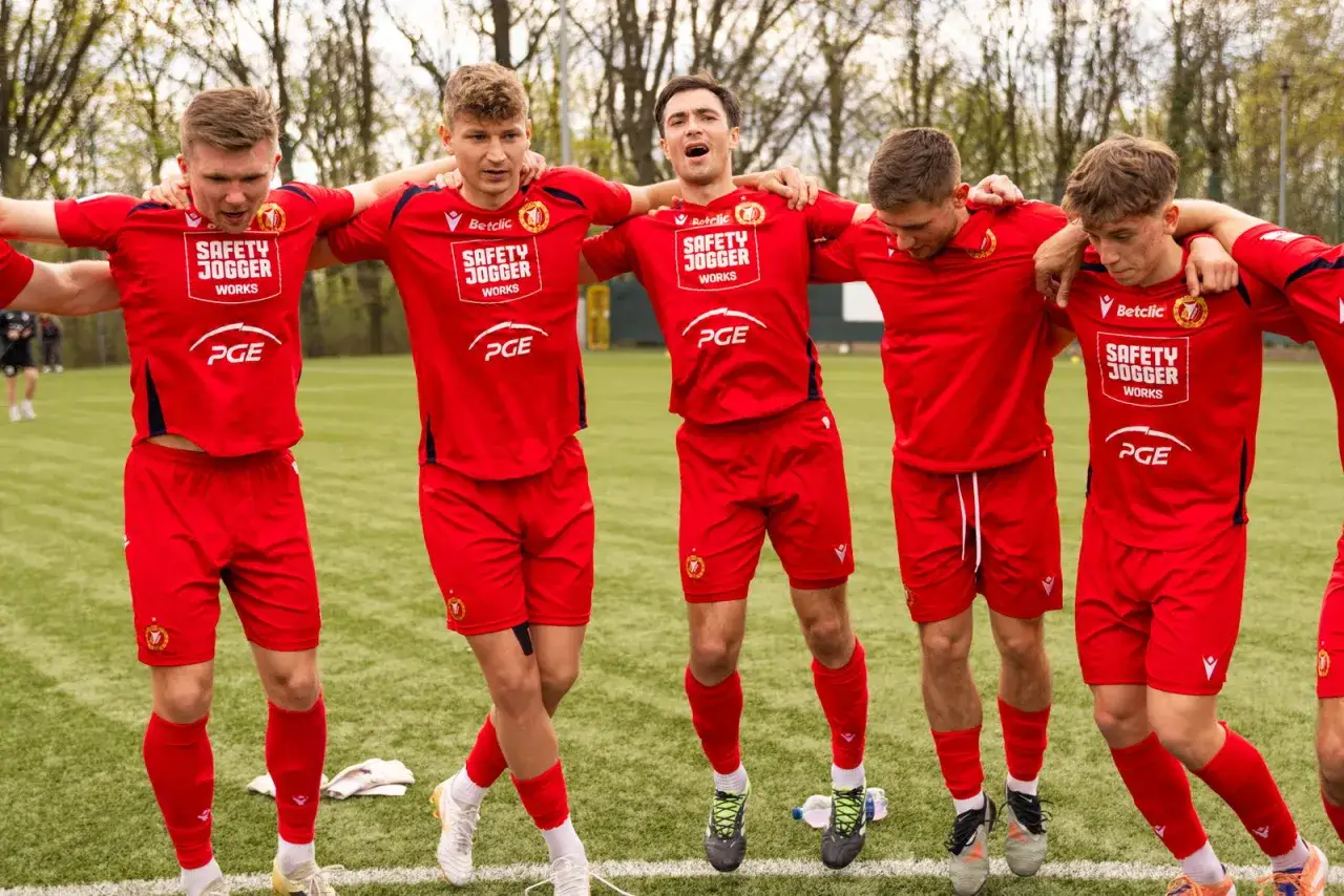 Pięciu piłkarzy w czerwonych strojach z logo Widzewa Łódź świętuje na boisku. Nowe widzew łódź transfery przyniosły radość!