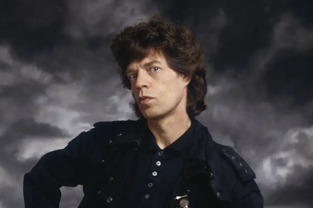 Mick Jagger, ikona rocka, w czarnej kurtce. Jego spojrzenie sugeruje energię, która towarzyszy jego niezapomnianym utworom.