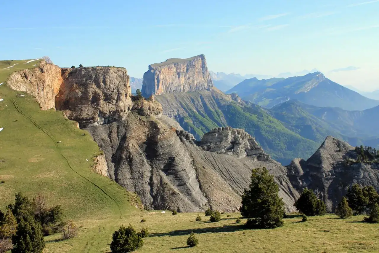 Paysage spectaculaire du Vercors, avec des falaises abruptes, des montagnes verdoyantes et un ciel bleu clair. Id&eacute;al pour un trek inoubliable.