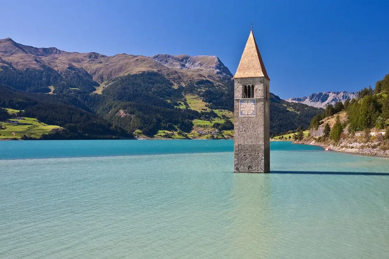 Der versunkene Kirchturm ragt aus dem t&uuml;rkisfarbenen Wasser des Reschensees. Ein malerischer Anblick, der zum Baden und Staunen einl&auml;dt.