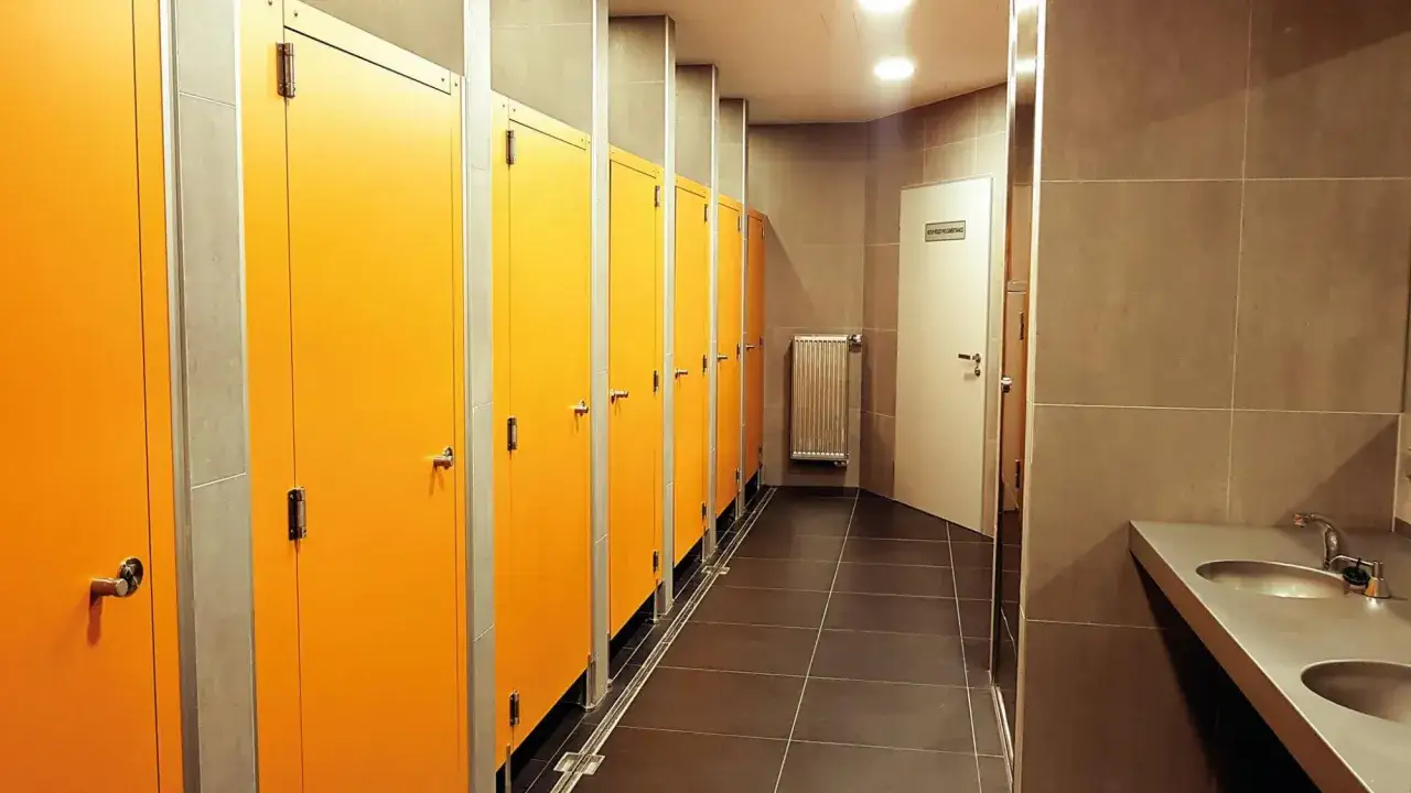 Pomieszczenie z rzędem pomarańczowych drzwi, które mogą prowadzić do pryszniców na stacjach paliw.
