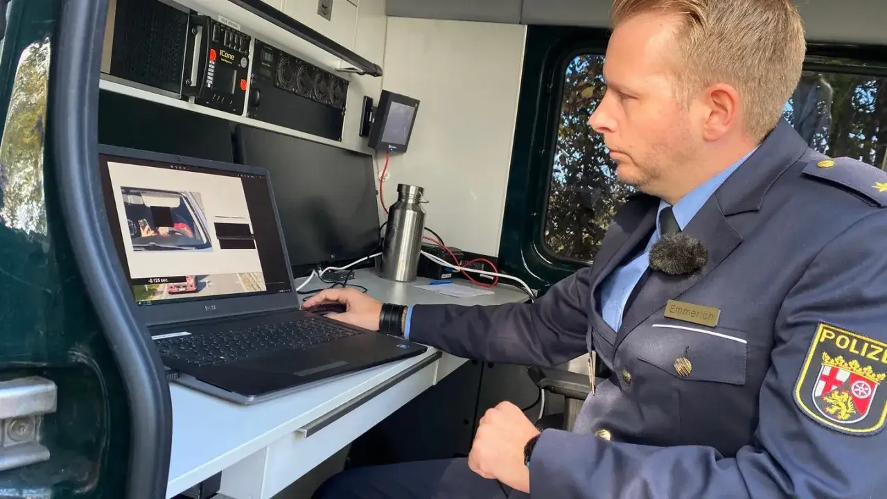 Polizist pr&uuml;ft Beweisfotos: Ein Fahrer wurde geblitzt mit Handy in der Hand.