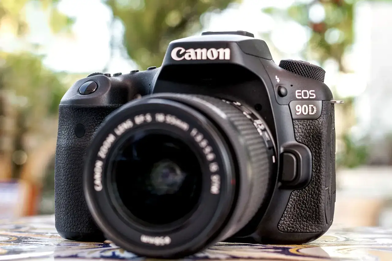 Czarny aparat Canon EOS 90D z obiektywem na stole. Idealny do uchwycenia każdej chwili.