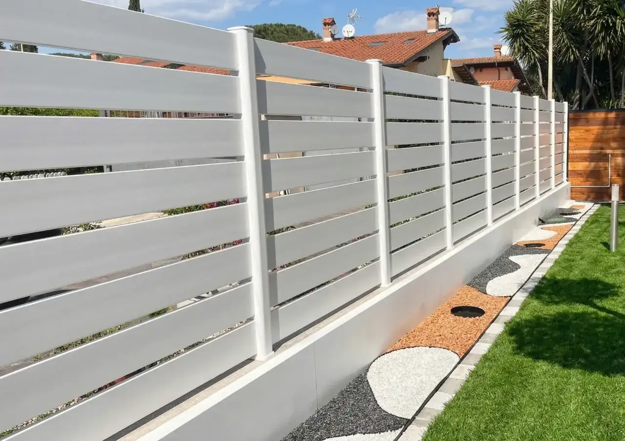 Recinzione moderna bianca a listelli orizzontali, con aiuola decorativa a ghiaia colorata. Un esempio di come fare una recinzione elegante e funzionale.