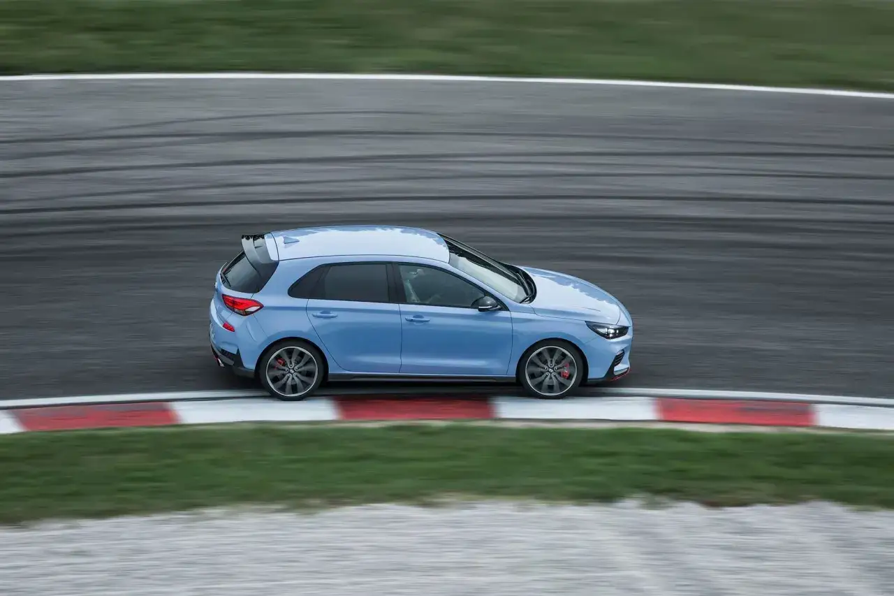Niebieski Hyundai i30 N na torze wyścigowym, z widocznymi śladami opon na asfalcie.