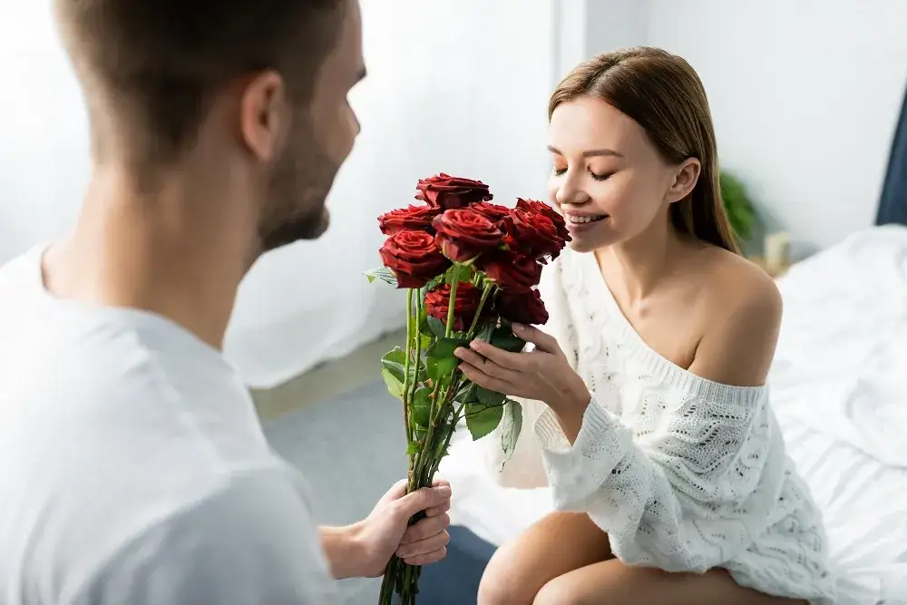 elegancki mężczyzna wręczający bukiet róż kobiecie na randce