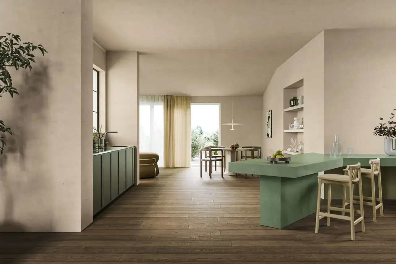 Interni moderni con cucina verde, isola e zona pranzo. Le pareti color calce viva formula creano un'atmosfera calda e naturale.