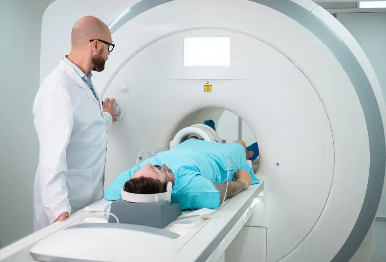 Pacjent leży w rezonansie magnetycznym, a lekarz przygotowuje badanie. Sprawdź, jaka jest tomograf cena.