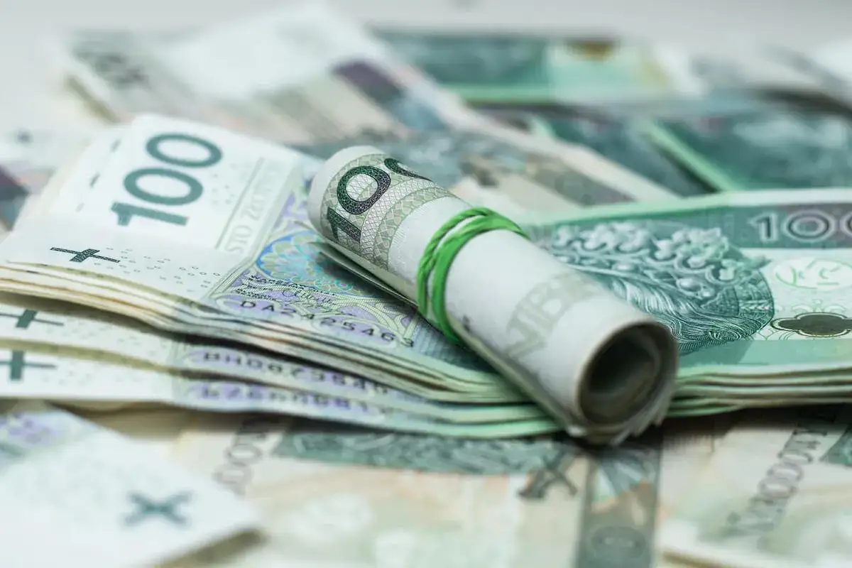 Zrolowane banknoty 100 zł, gotowe do spłaty zadłużenia u komornika przez osobę trzecią.