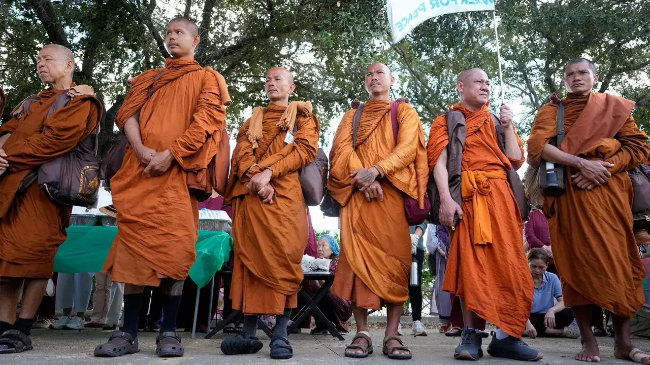 Monks in orange robes stand together. Their serene expressions hint at a life dedicated to peace, raising questions about how long do monks live.
