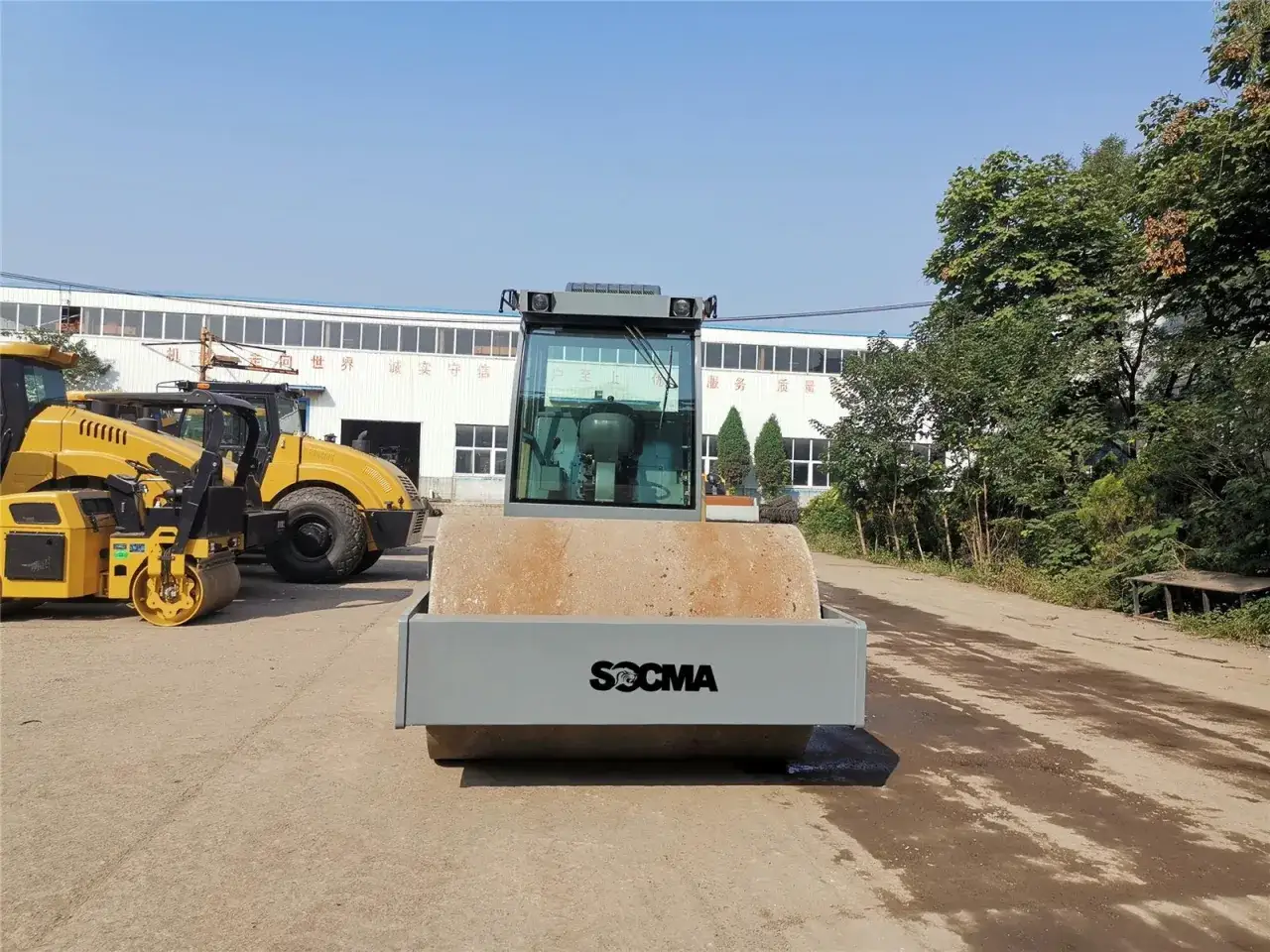 Nowy walec drogowy SOCMA gotowy do pracy. Obok stoją inne maszyny budowlane.