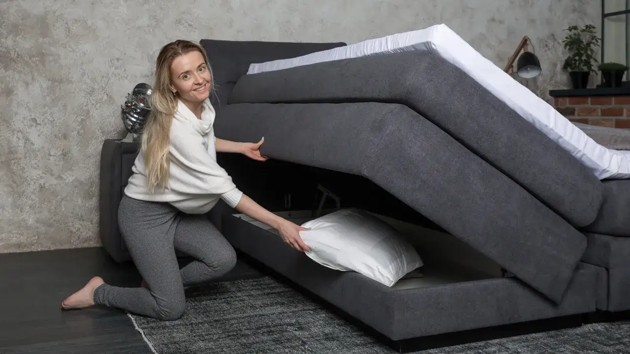 Frau verstaut Kissen in einem Boxspringbett mit Stauraum. So beziehe ich ein Boxspringbett – mit praktischem Platzangebot.