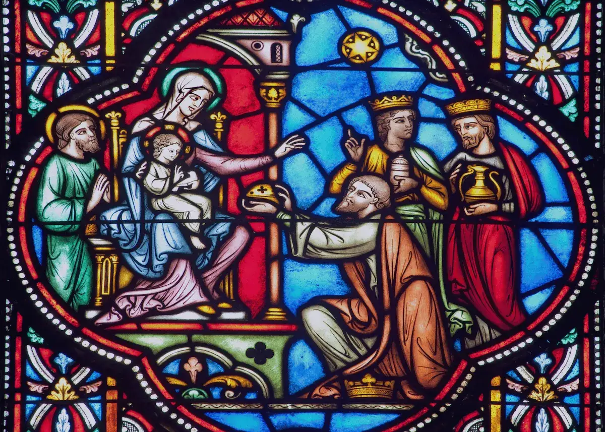 Stained glass depicting the Adoration of the Magi, a scene often featured in catholic homilies on the Epiphany, with Mary holding Jesus, Joseph, and the three kings.