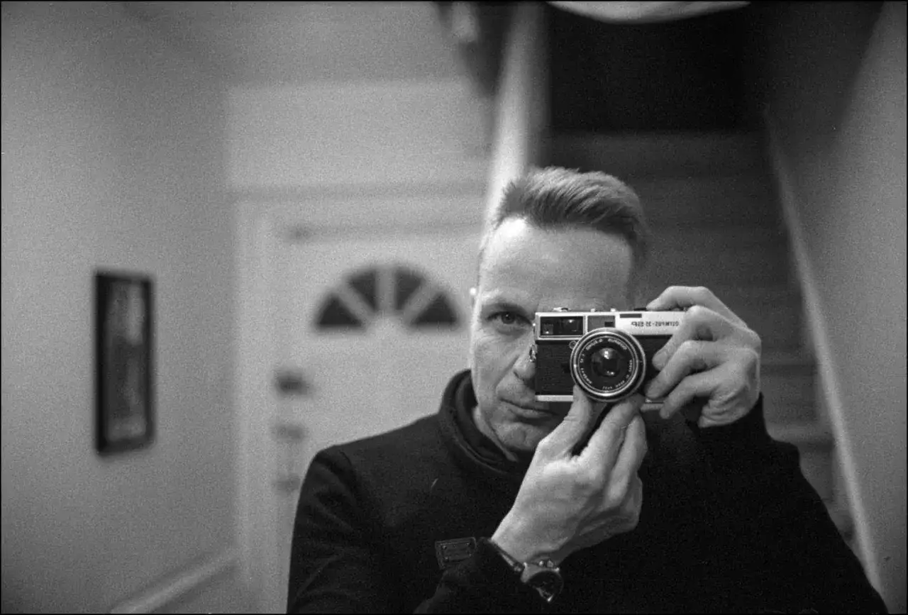 Man takes a selfie with his Olympus rangefinder camera, capturing a moment of reflection.