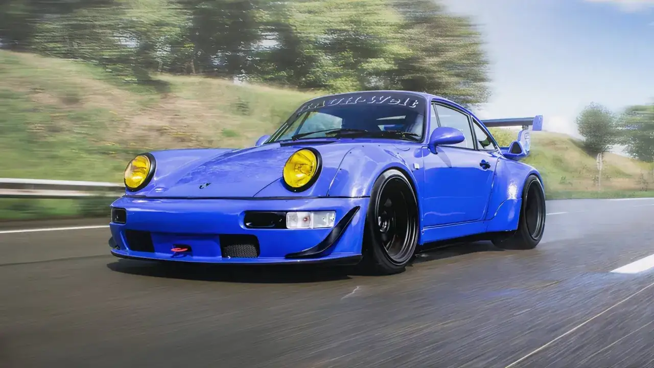 Niebieski Porsche RWB z żółtymi reflektorami i wielkim skrzydłem pędzi po krętej drodze wśród zieleni.