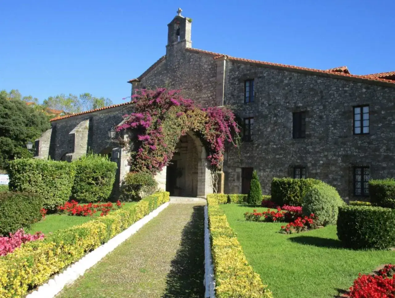 El santuario de la Barquera, con su entrada adornada de flores, invita a la paz. Un camino de piedra serpentea entre jardines cuidados.