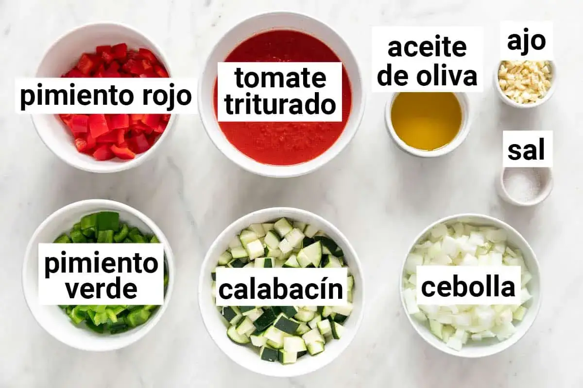 Ingredientes para hacer pisto: pimiento rojo y verde picados, calabacín en cubos, tomate triturado, cebolla picada, ajo, aceite de oliva y sal.