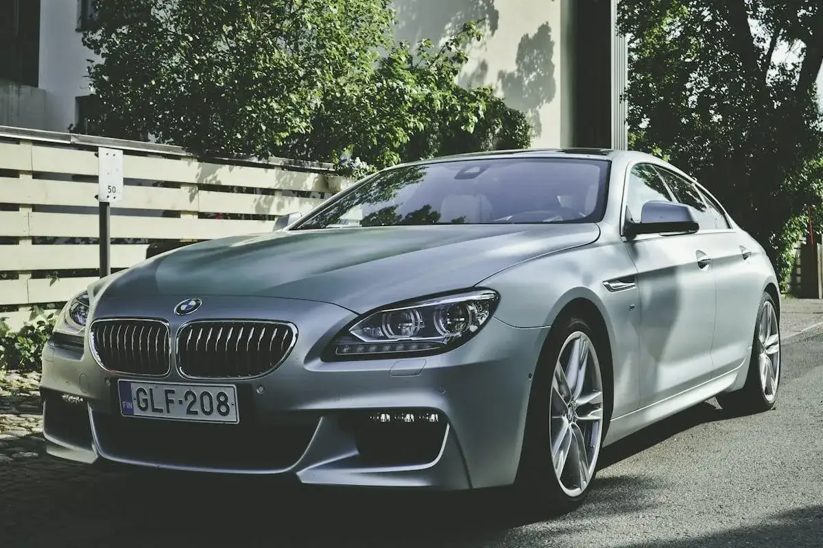 En silverf&auml;rgad BMW st&aring;r parkerad p&aring; en gata. Bilen har en elegant design och ser ut att vara i toppskick, n&auml;stan som en grekisk bil i sin sk&ouml;nhet.