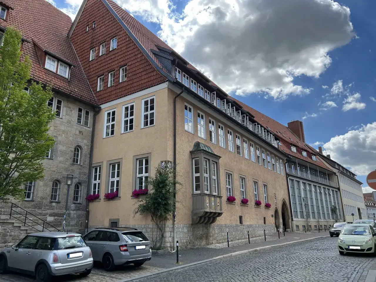 Das Mariano Josephinum, ein historisches Gebäude mit roten Ziegeldächern und vielen Fenstern, steht an einer kopfsteingepflasterten Straße.