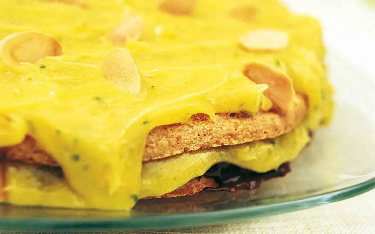 En ljusgul tårta med mandelflagor, täckt av krämig lime curd.