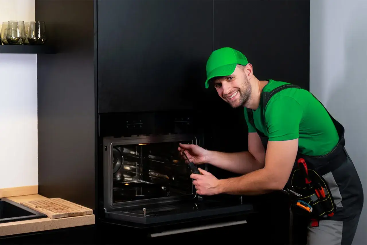 Ein Techniker repariert einen Backofen, der nicht mehr heizt. Er hat Werkzeug dabei und l&auml;chelt zuversichtlich.