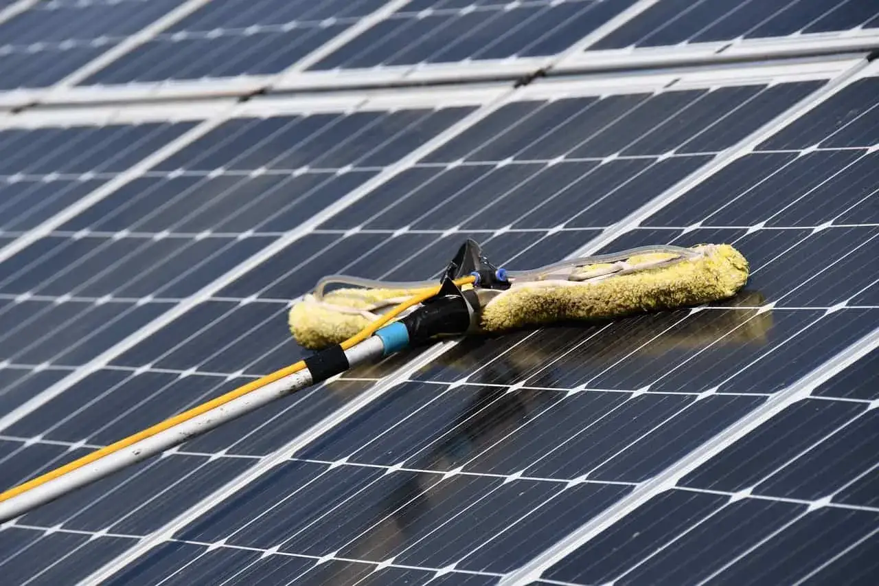 Ein Reinigungswerkzeug mit gelbem Bezug wird über eine Reihe von Solaranlagen geführt. Die solaranlagen reinigung sorgt für maximale Effizienz.