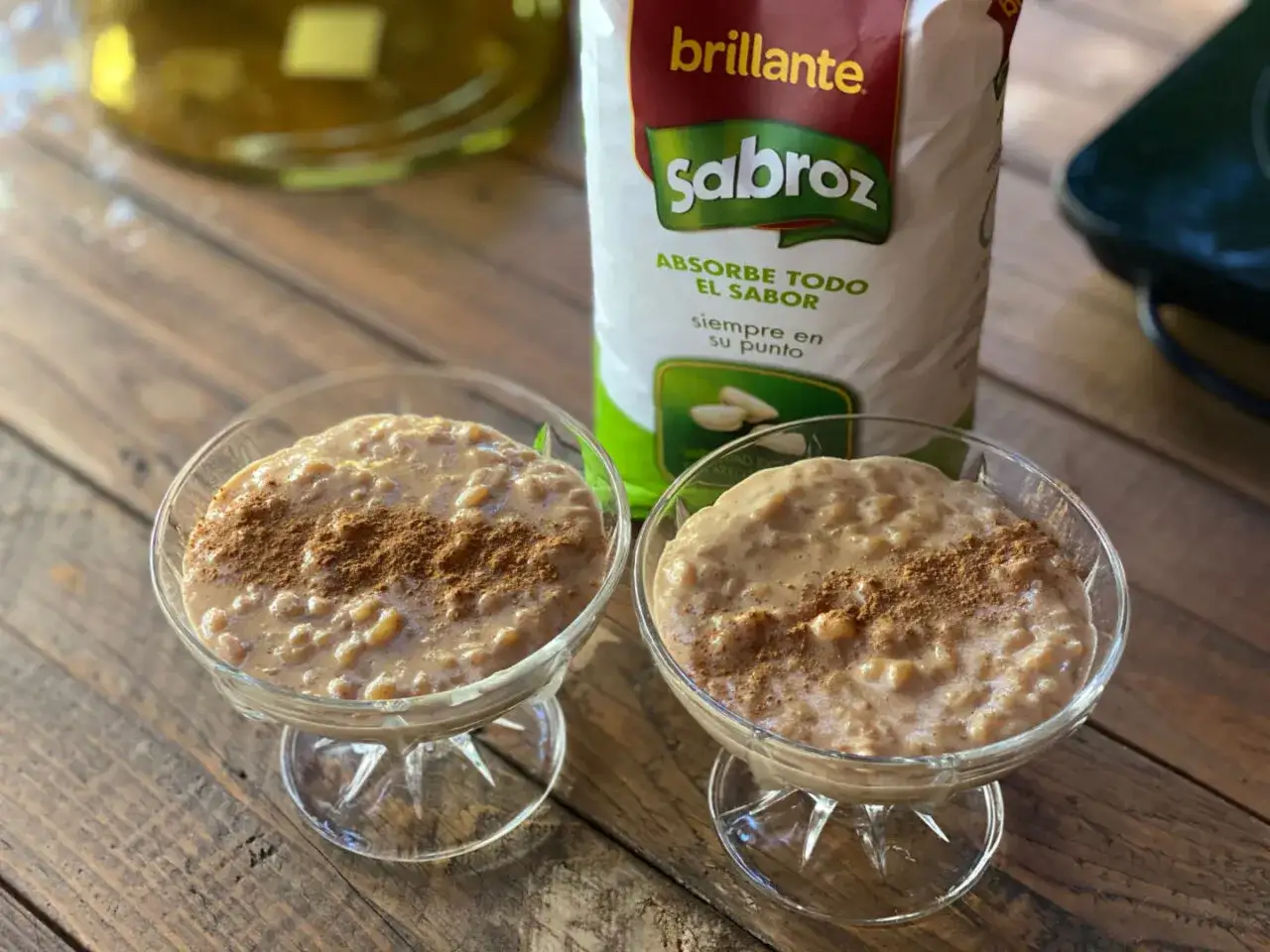 Dos copas de cremoso arroz con leche, espolvoreado con canela, listas para disfrutar. Detrás, un paquete de arroz Sabroz.