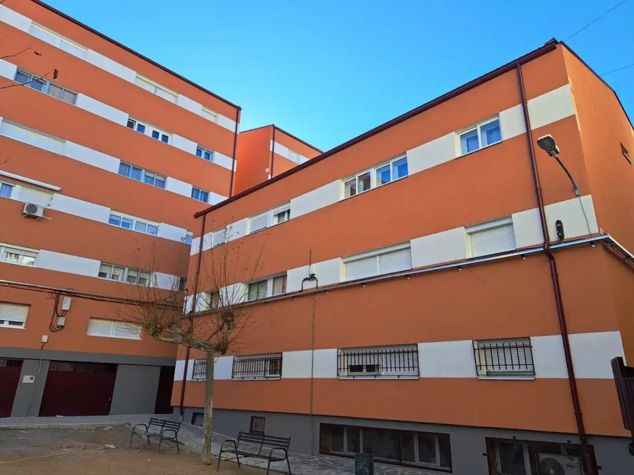 Edificios residenciales con fachada naranja y franjas blancas, resultado de una **rehabilitación de edificios** que les ha dado un nuevo aire.