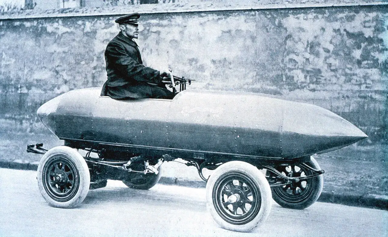 Hombre con gorra conduce un prototipo de coche eléctrico, un hito en la historia del coche eléctrico.