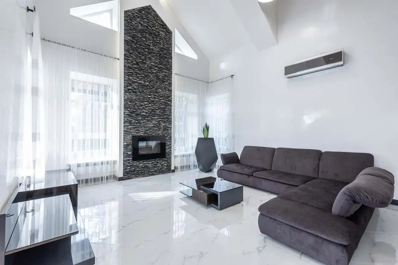 Nowoczesny salon z kominkiem i kanapą. Klimatyzator 2.5 kW zapewni komfort w pomieszczeniu do 25 m².