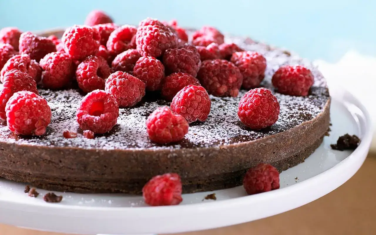 En läcker glutenfri kladdkaka toppad med färska hallon och pudrad florsocker. Perfekt för alla tillfällen!