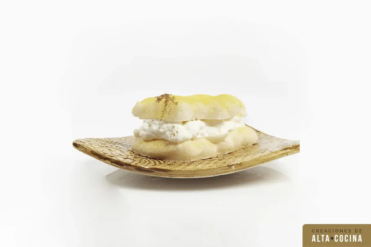 Delicado pastel ruso con crema batida, espolvoreado con canela, servido en un plato texturizado.