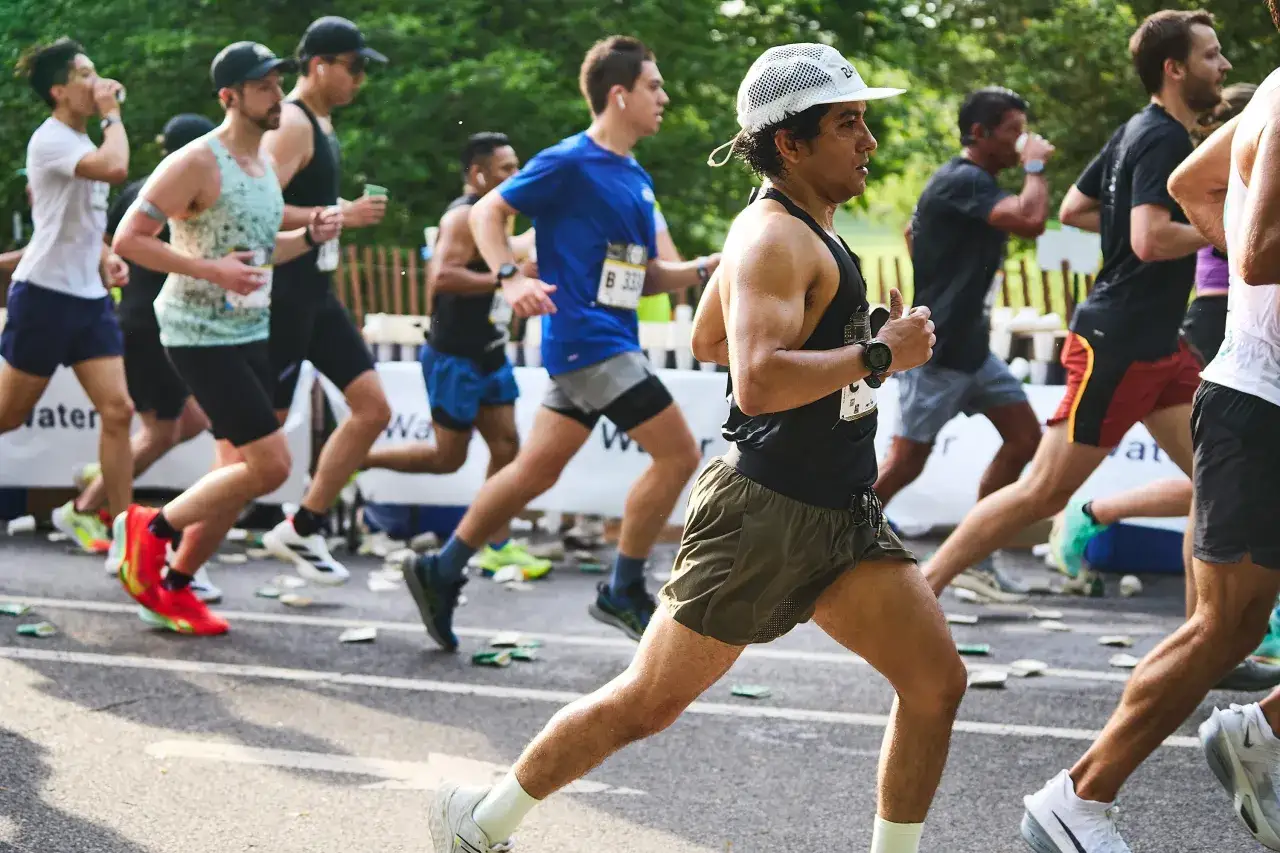 Biegacze w r&oacute;żnym tempie pokonują trasę maratonu. Widać ich skupienie i wysiłek.