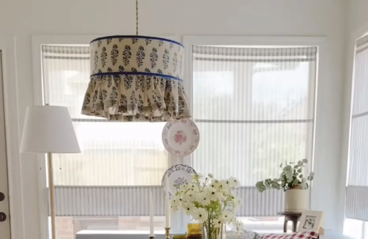 Abat jour DIY avec un tissu fleuri bleu et blanc, bord&eacute; de volants. Une lampe sur pied blanc est &agrave; gauche.