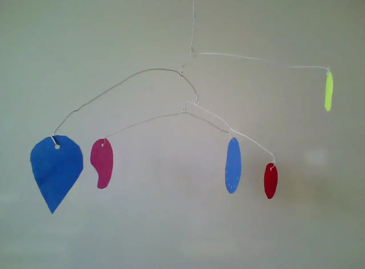 Mobile Calder maternelle aux formes colorées : un cœur bleu, des gouttes roses et bleues, et une forme jaune.