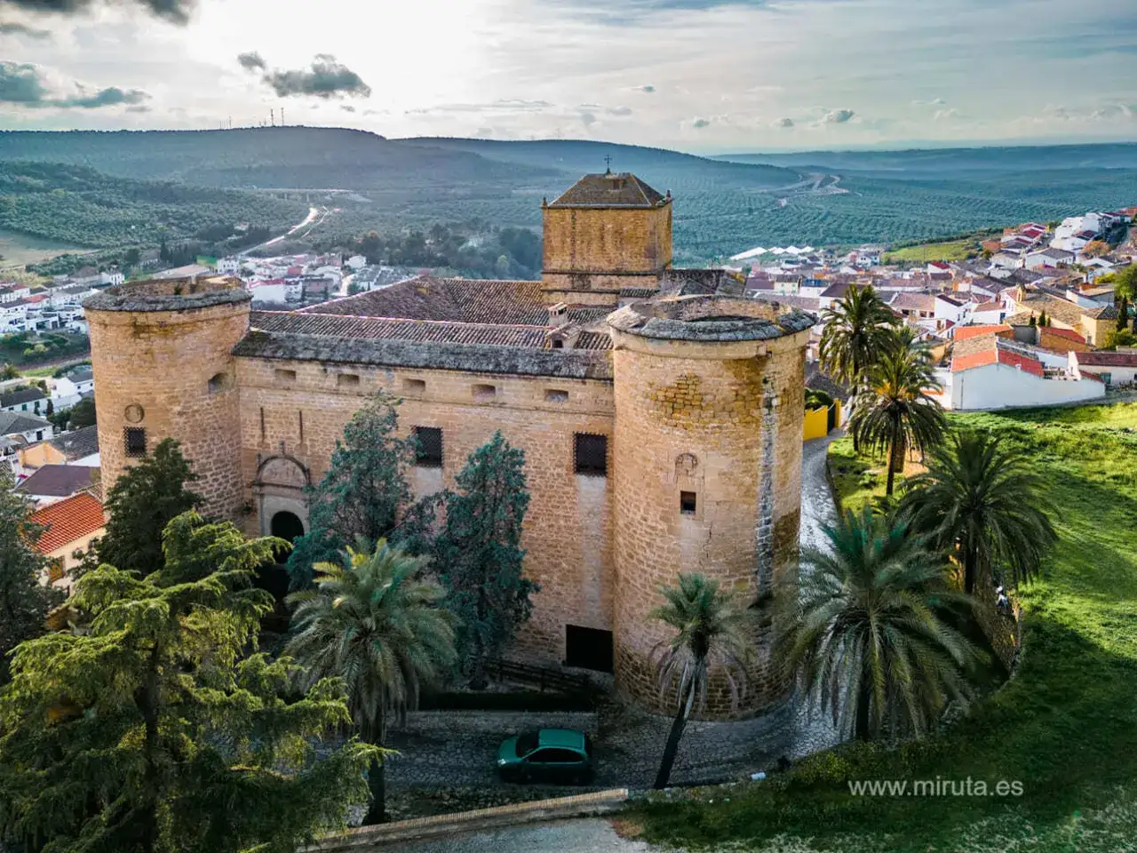 Castillo de Baños de la Encina, un lugar imprescindible que ver en Jaén. Palmeras y olivos rodean esta fortaleza histórica.