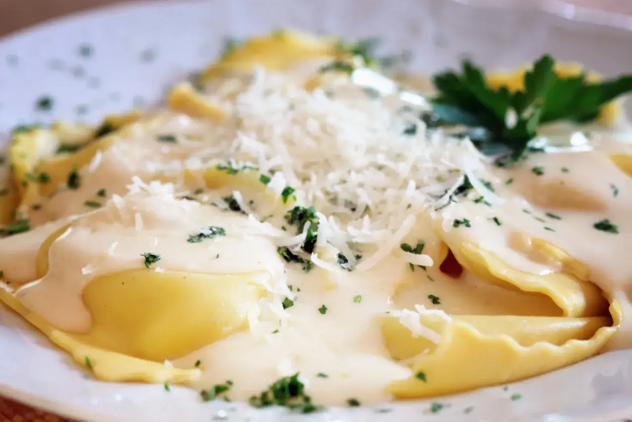 Raviolis dorés nappés d'une sauce crémeuse, parsemés de parmesan râpé et de persil frais. Un délice de ravioli truffe.