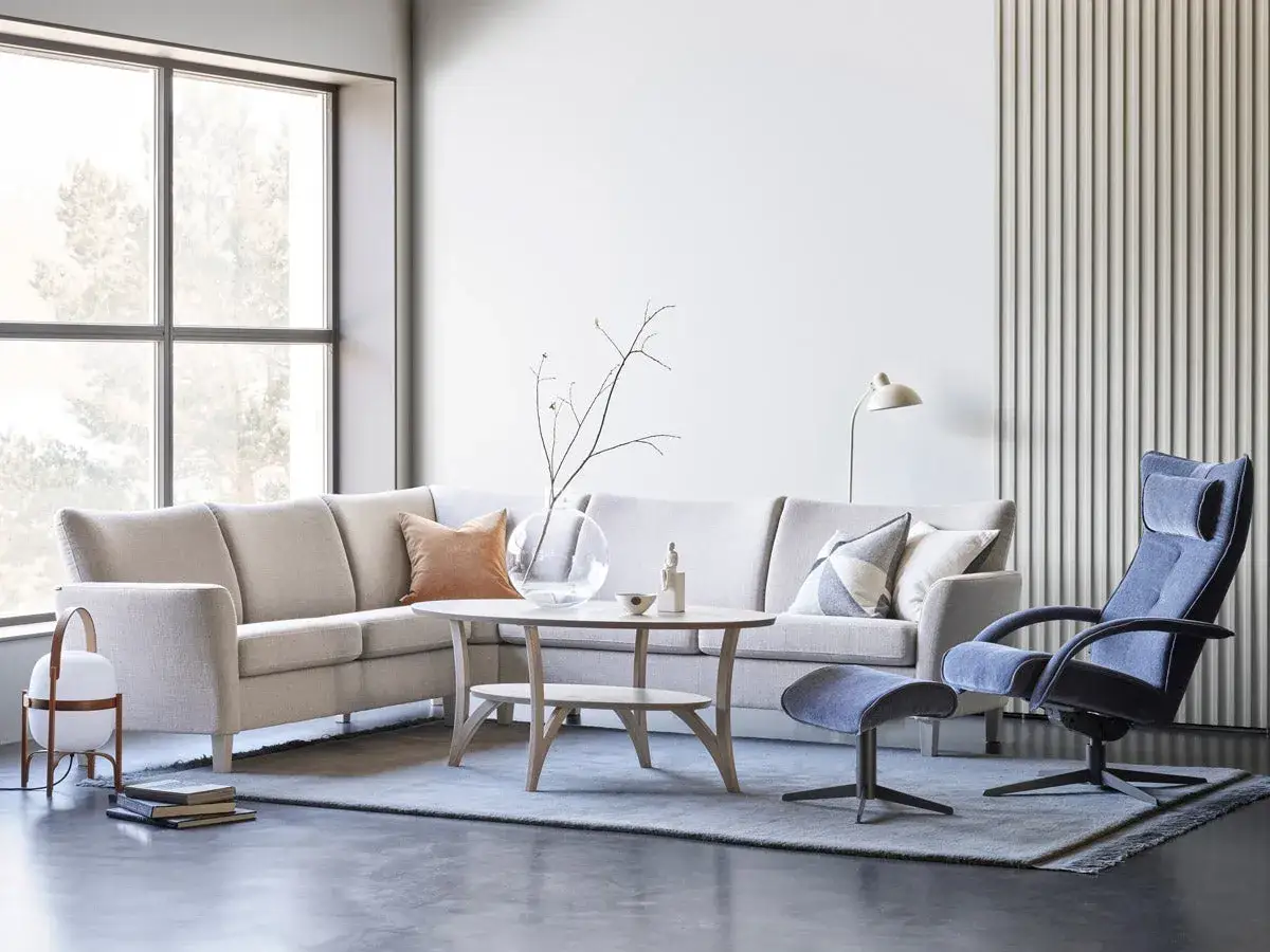 En ljus och modern lounge med en bekv&auml;m brunstad f&aring;t&ouml;lj, soffa och ett runt soffbord.