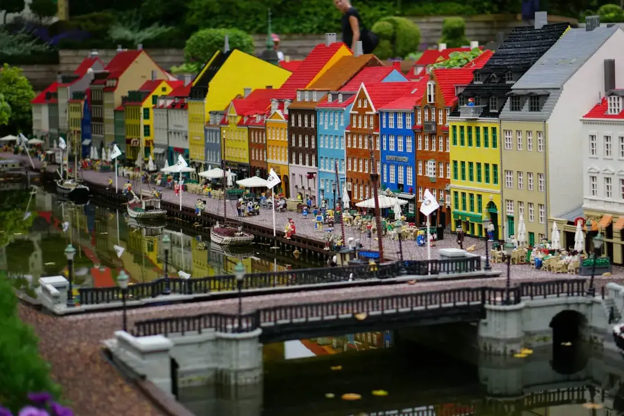 Kolorowe kamienice nad kanałem, łodzie i mostek w miniaturowym świecie Legoland Dania.