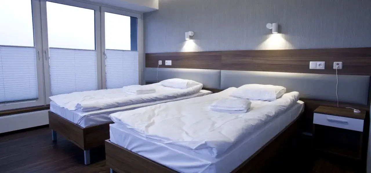 Pokój w sanatorium z dwoma łóżkami, czystą pościelą i oknem. Czy to miejsce zasługuje na dobre sanatorium kos opinie?
