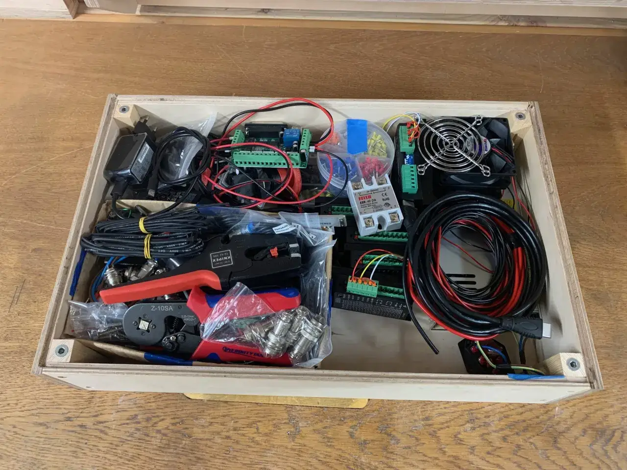Zestaw elementów do budowy frezarki CNC DIY: sterowniki, kable, złącza, narzędzia i wentylator.
