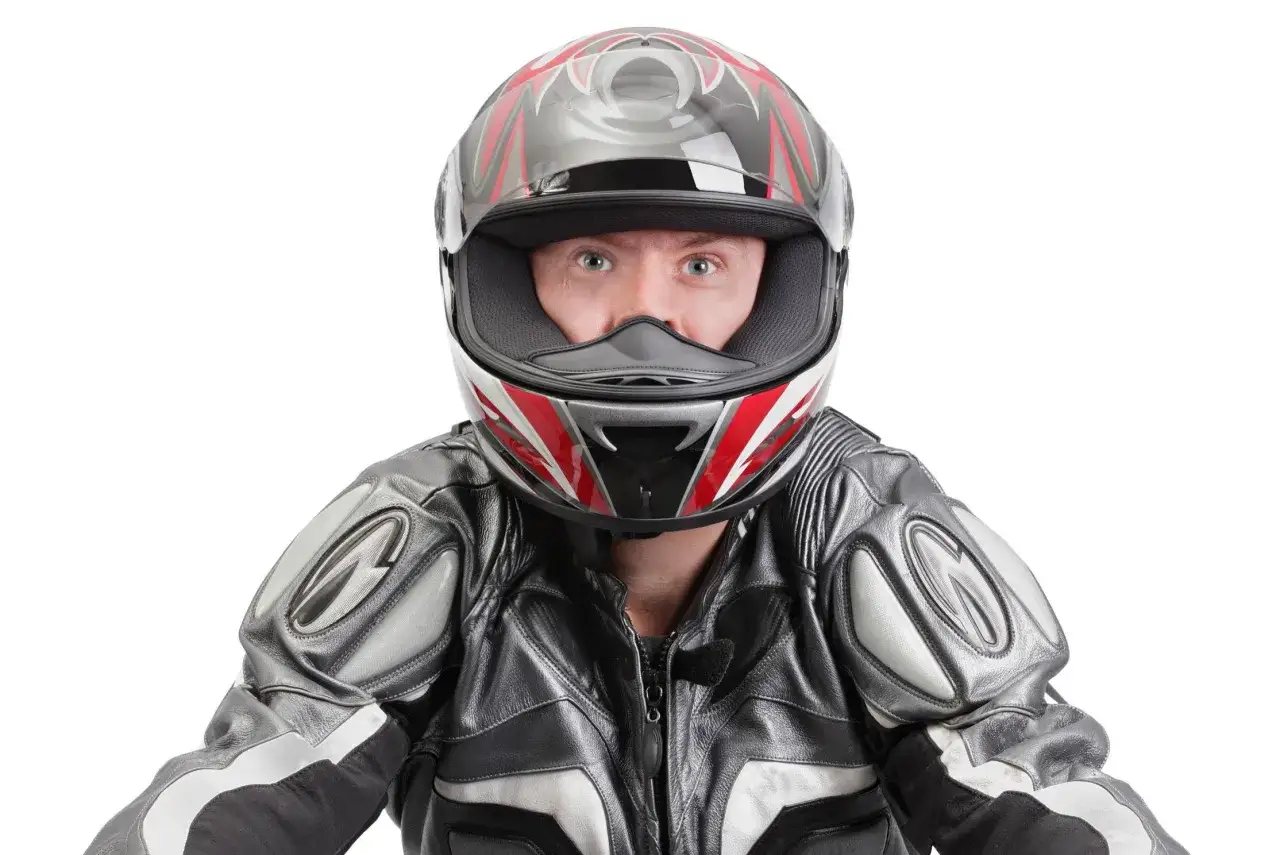 Occhi spalancati dietro un casco stretto, pronto per la corsa. La tuta in pelle grigia e nera completa il look da motociclista.