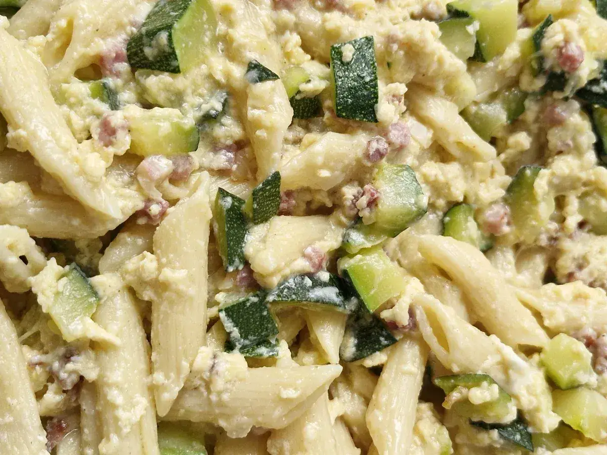 Penne mit cremiger Sauce, Speckwürfeln und grünen Zucchinischeiben. Eine köstliche Zucchini Carbonara.