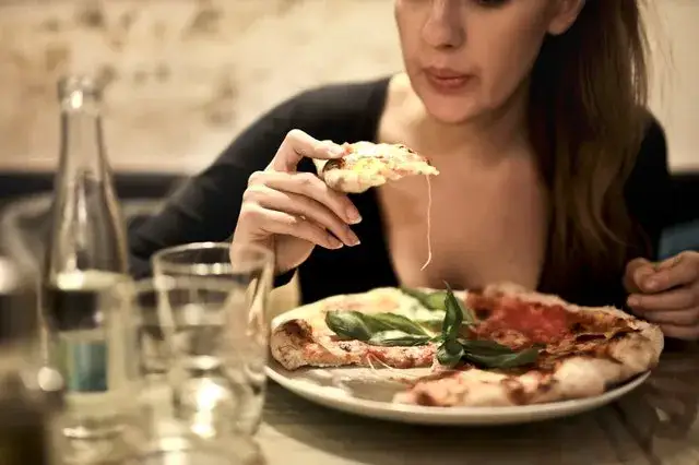 Włoch jedzący pizzę rękami